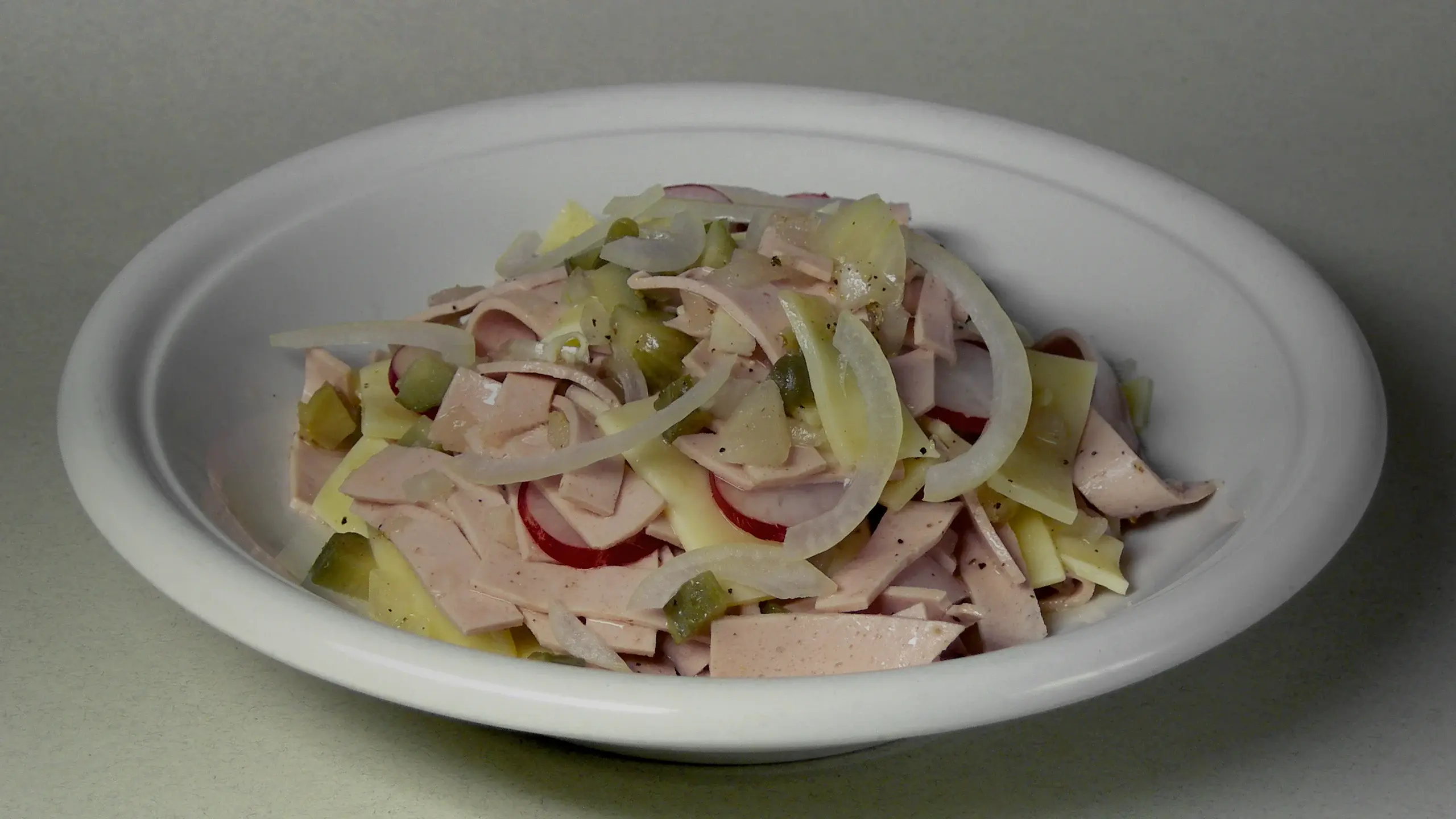 Assiette de salade de cervelas en julienne avec gruyere, oignon et cornichons