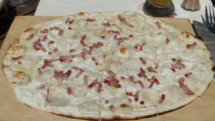 Flammekueche alsacienne cuite, pâte fine avec lardons et oignons dorés