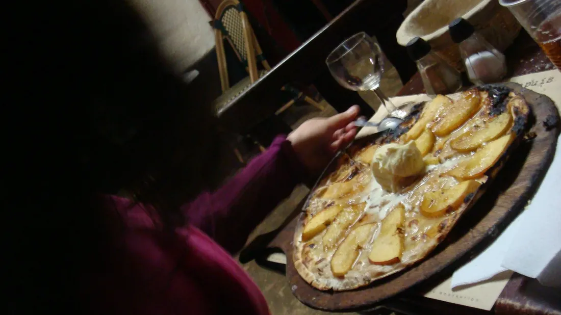 Tarte flambée gratinée sortant du four sur une planche