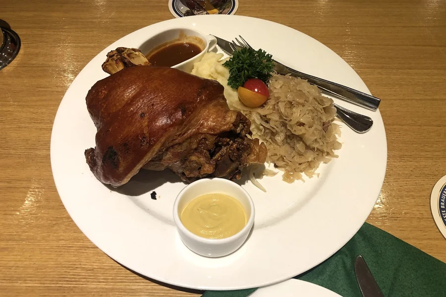 Jarret de porc rôti à la couenne brune servi sur un lit de choucroute avec sa sauce