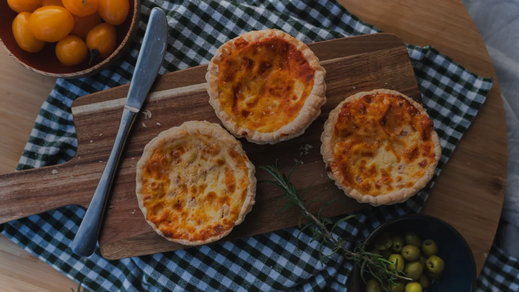 Petites tartes salées dorées sur une planche en bois