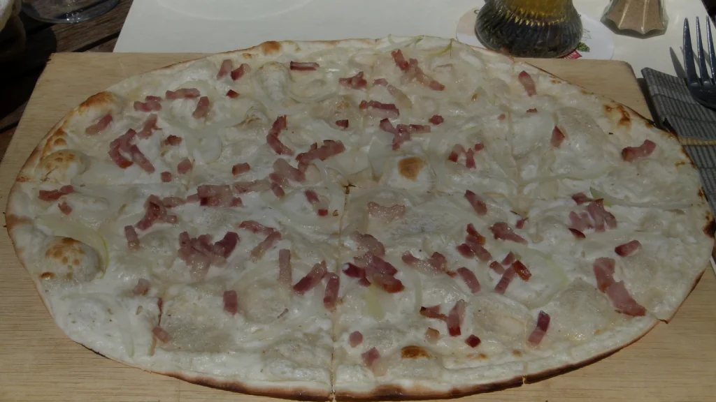 Tarte flambée aux oignons et lardons sur une planche