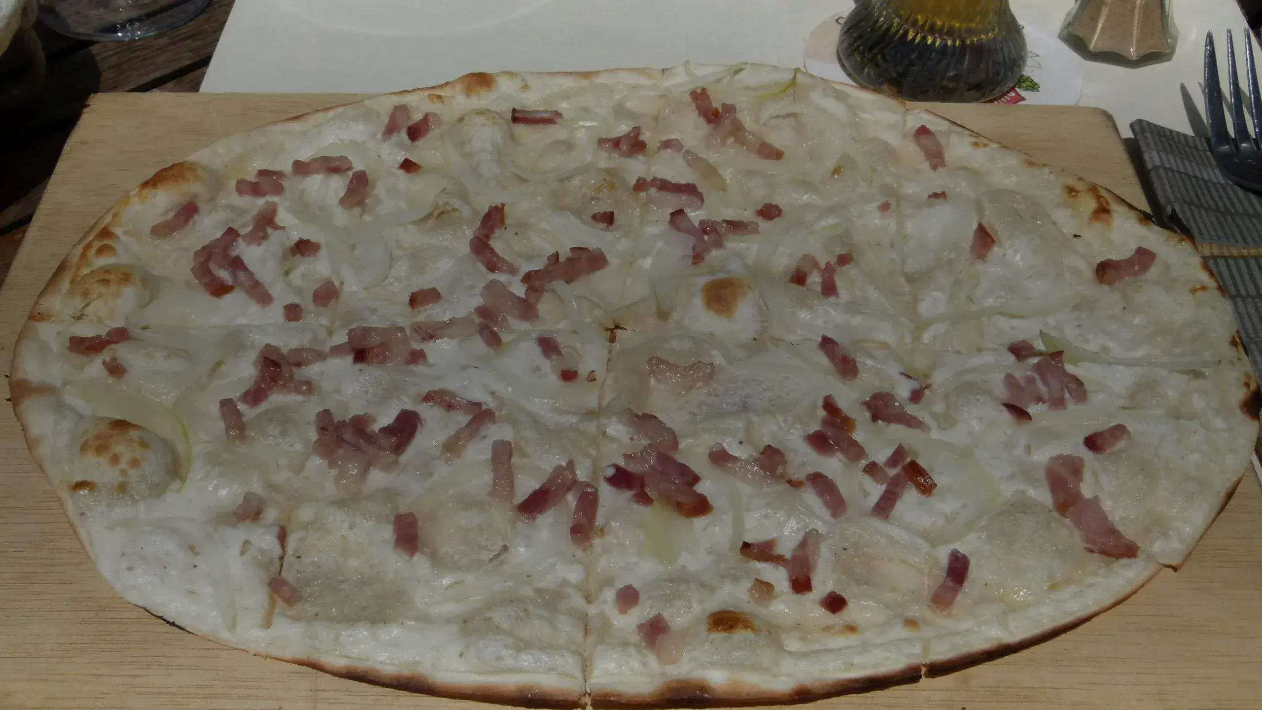 Tarte flambée aux oignons et lardons sur une planche