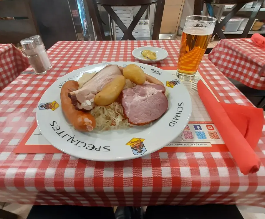 Assiette de choucroute garnie avec saucisses, lard et pommes de terre, servie avec un verre de bière