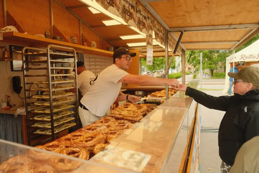 Un vendeur sert des bretzels frais à un client à un comptoir de marché